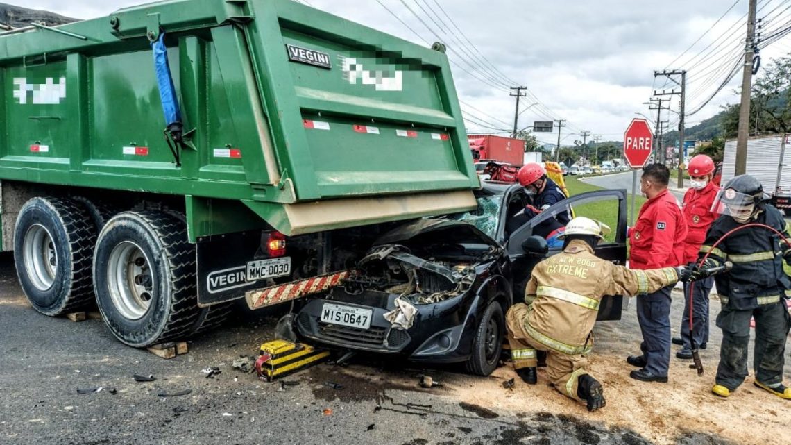 Automóvel fica destruído após colidir e ficar preso embaixo de caminhão