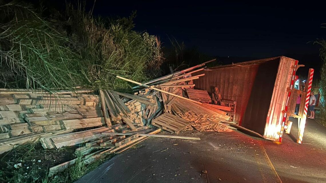 Caminhoneiro fica preso às ferragens após tombar com caminhão carregado de madeira